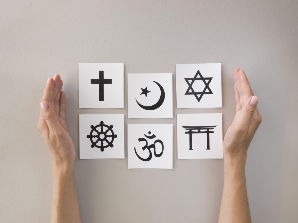 deux mains qui entourent six symboles des grandes religions. Source: freepik.com