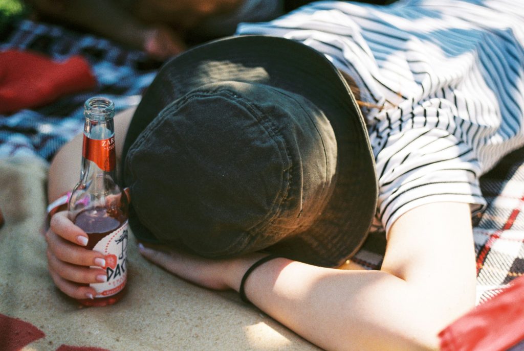 une personne couché par terre avec une bouteille en verre en main